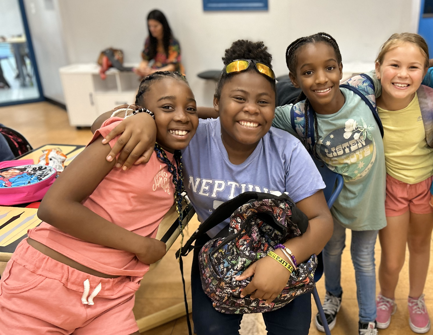 A group of four young friends smiling and hugging for a photo.