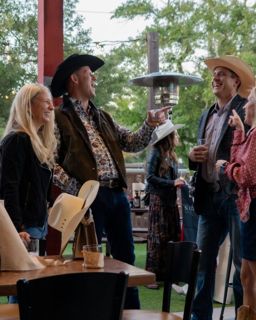 Friends in western attire socialising on an outdoor covered patio.